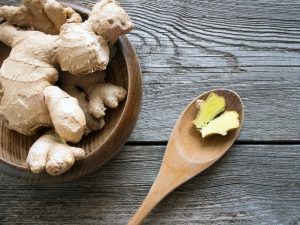 Ginger root in wooden bowl and spoon